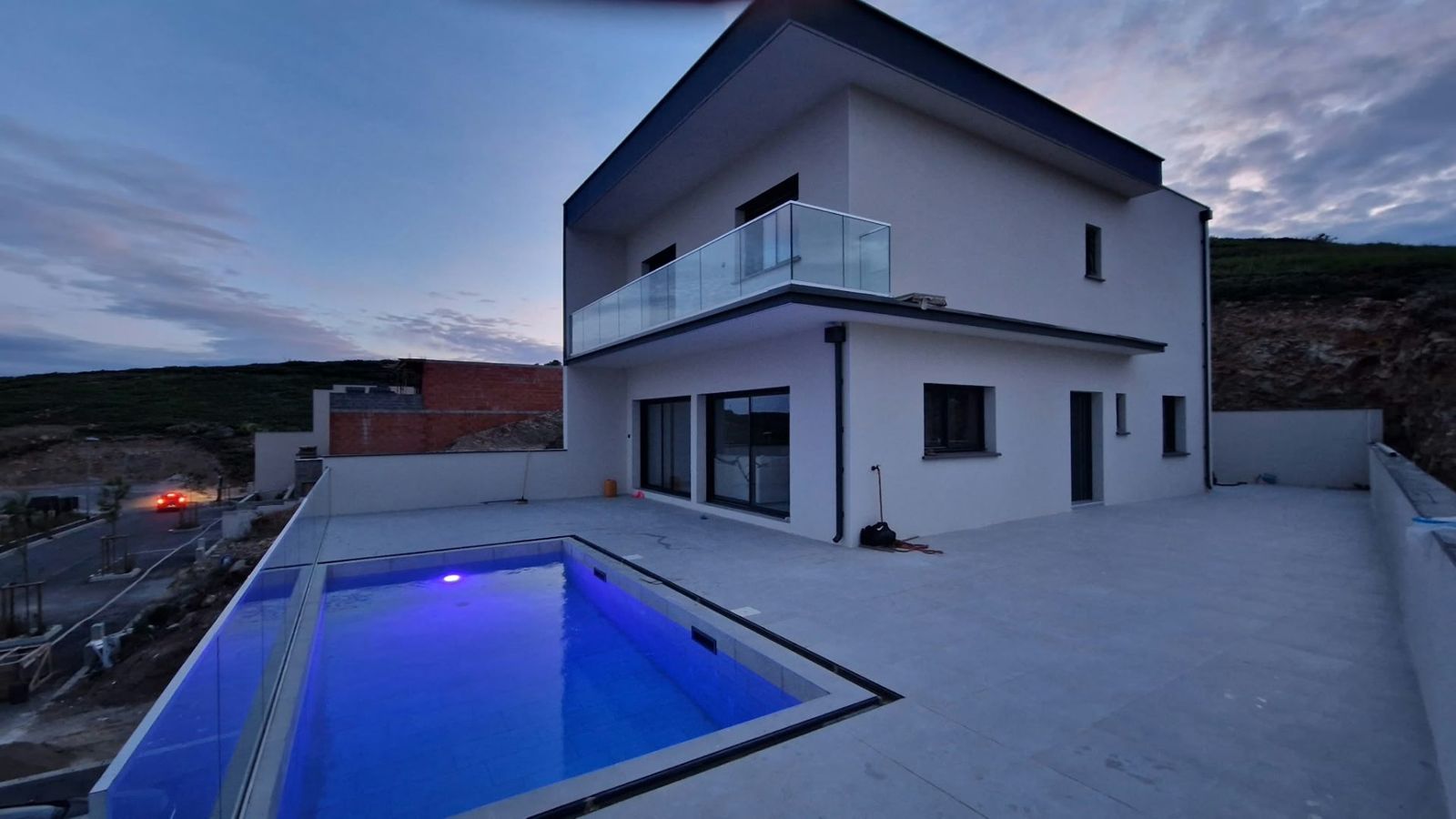 Maison contemporaine terminée avec piscine et terrasse, au crépuscule